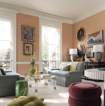 living room, orange walls, art on walls, maroon ottoman, green cushions