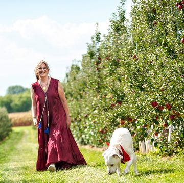 melissa gilbert in red long dress walking in apple orchard with dog