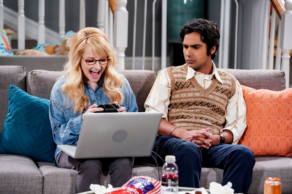 un hombre y una mujer sentados en un sofá con una computadora portátil