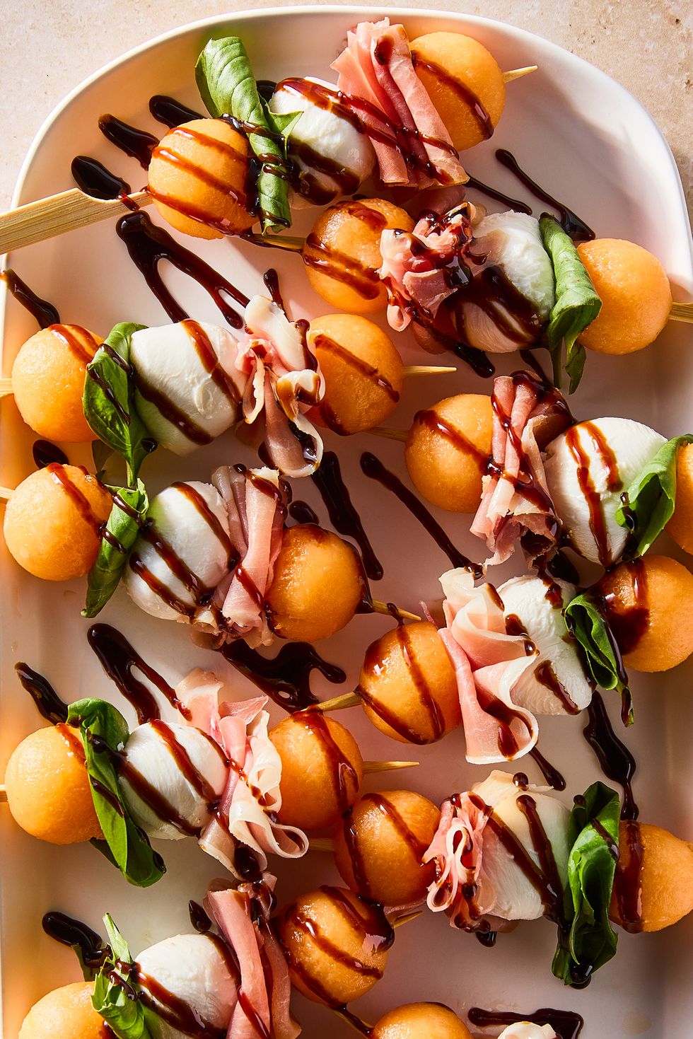 skewers with cantaloupe balls, mozzarella balls, and fresh basil leaves drizzled with balsamic glaze