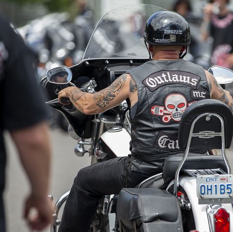 a motorcycle rider wearing a leather jacket with a skull and pistons logo