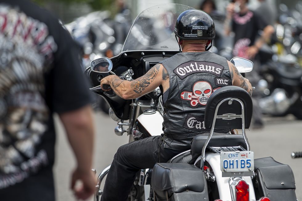 a motorcycle rider wearing a leather jacket with a skull and pistons logo