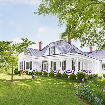 a white farmhouse is decorated with red white and blue bunting that hangs on the porch