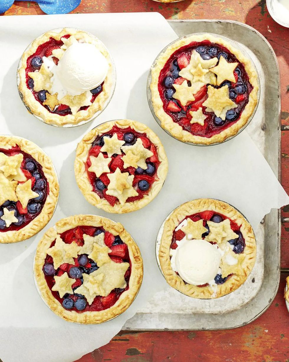 mini stars berry pies arranged on a metal serving tray and a couple with a scoop of vanilla ice cream on top