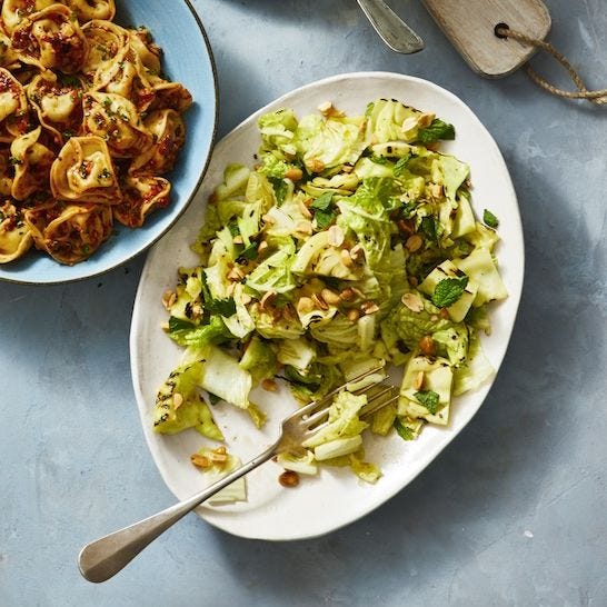 grilled cabbage in a dressing with chopped peanuts on a white plate