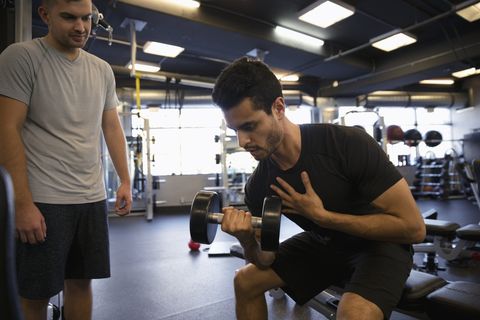 Men exercising, doing biceps curls with dumbbell in gym