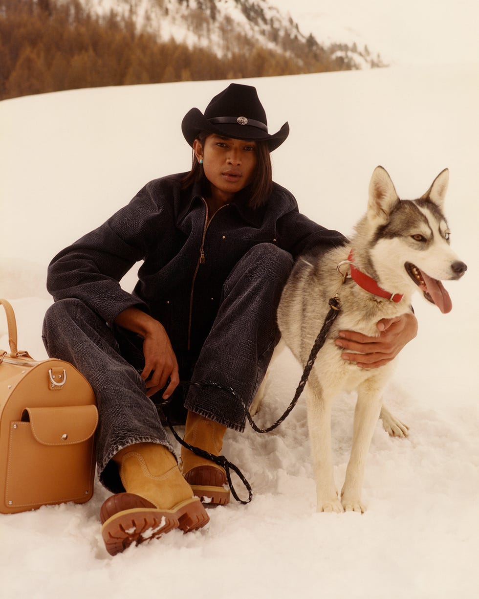 Una persona sentada con un perro en la nieve.