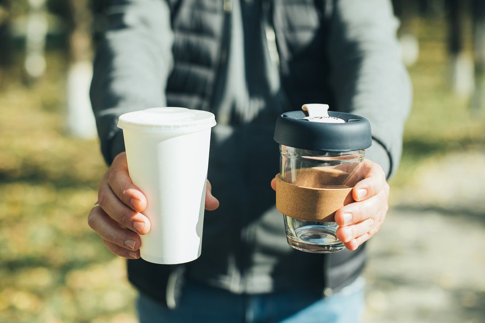 men holding takeaway coffee cup and disposable paper cup with plastic lid conscious choice