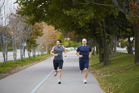 men jogging on footpath in autumn city