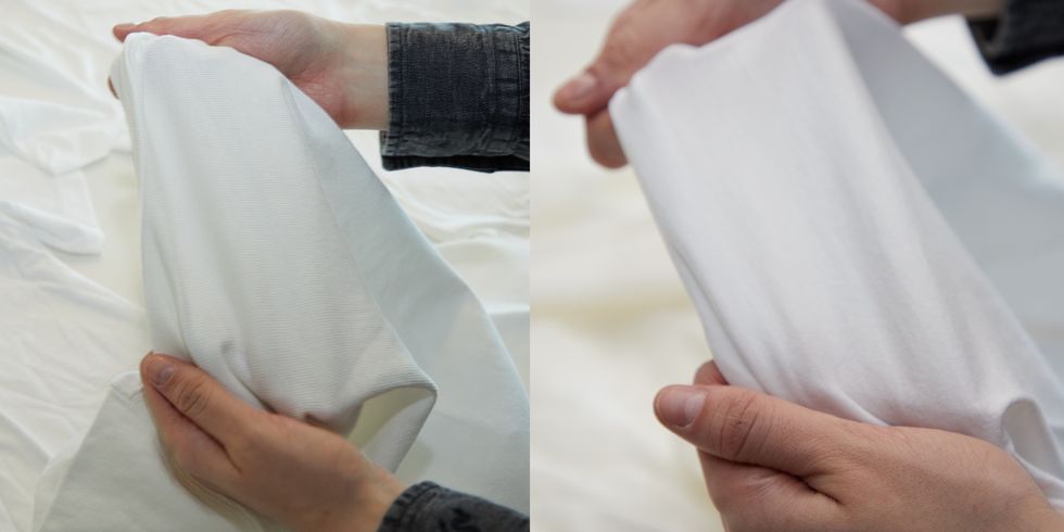 a person's hands holding a white t shirt