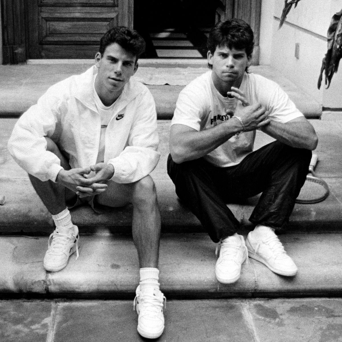 two men sitting on a porch step and folding their hands