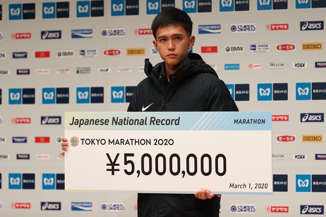 suguru osako posa con el premo de 5 millones de yenes por haber batido el récord japonés de maratón en tokio