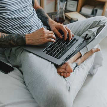man in jogger sweatpants sitting on cough with laptop