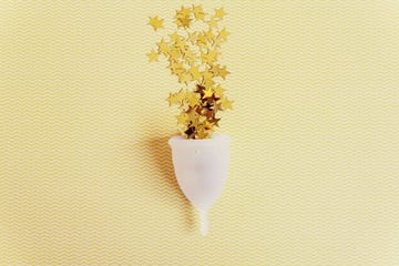 menstrual cup with sparkling stars on yellow background