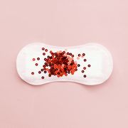 Menstrual pad with red glitter on pastel background