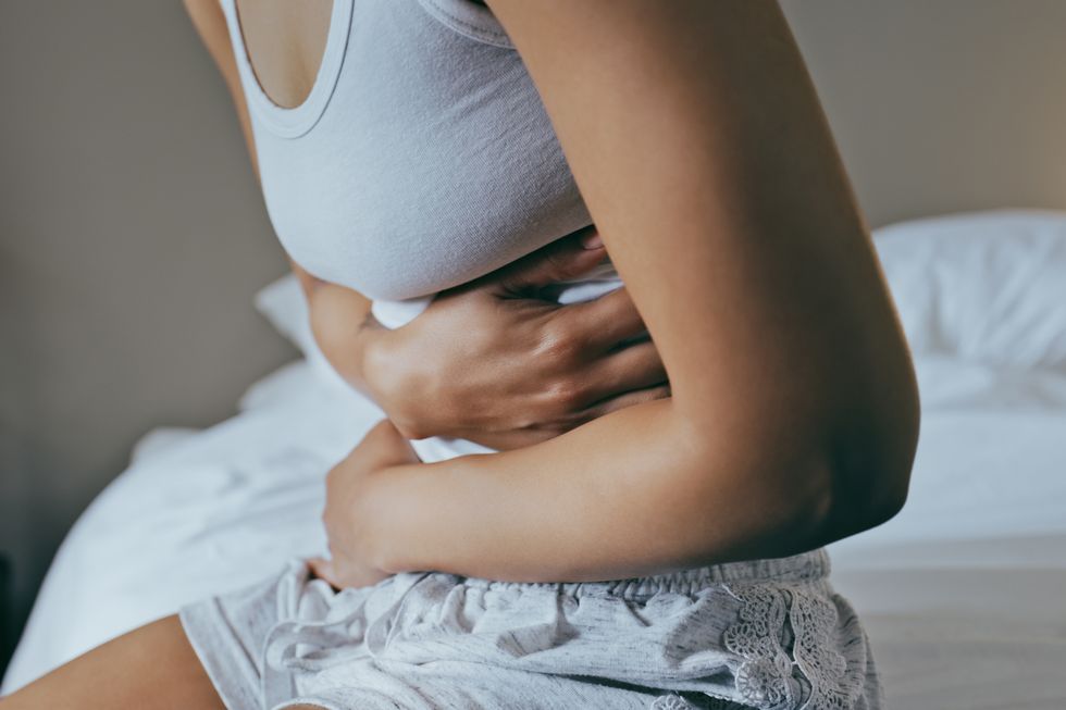menstruation, stomach ache and hands of woman in bedroom for indigestion, cramps and illness frustrated, gas and stress with girl on bed for constipation, bloating and intestine problems at home