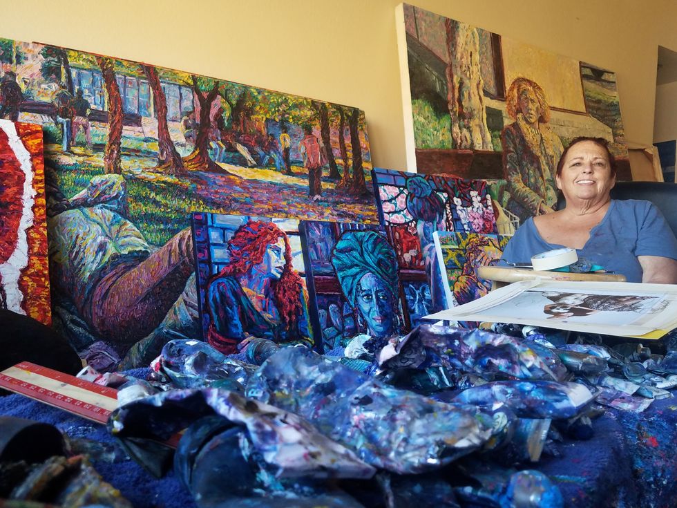 meridy voz surrounded by paintings in her studio