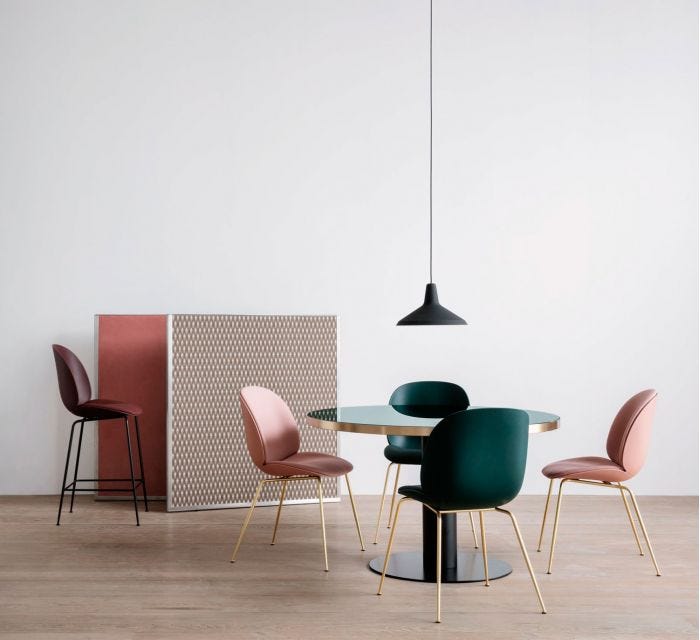 Mesa de comedor con estructura negra, sobre de cristal color bottle green y perfil de latón