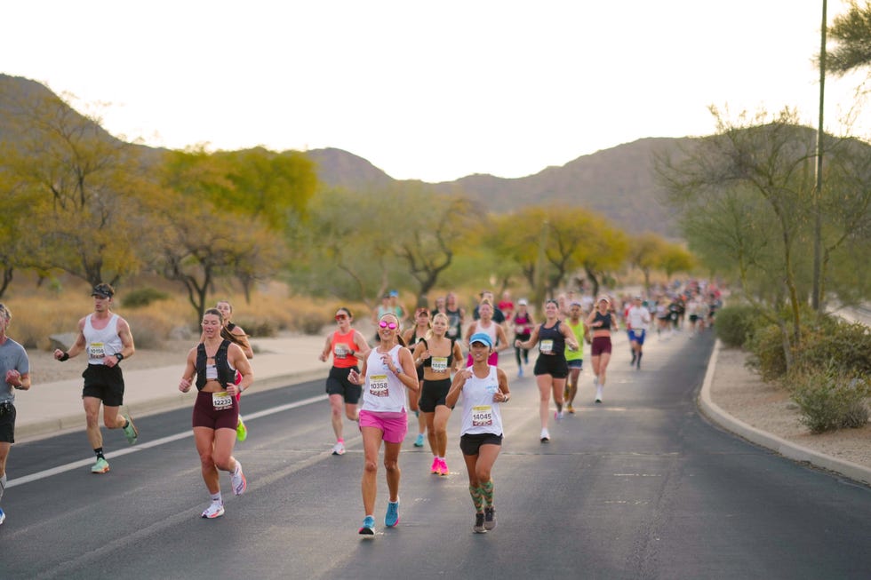 participants running in a marathon on a road with mountains in the background