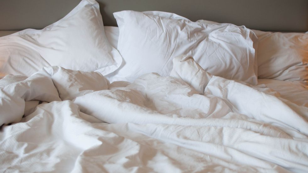 a messy bed with comforter and pillows