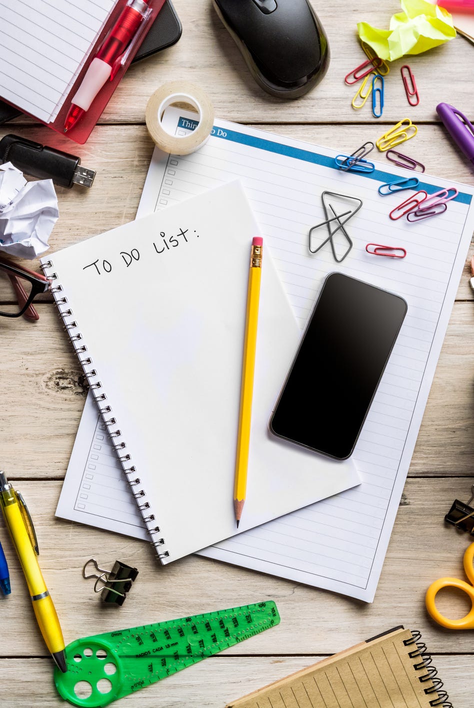 messy desktop with office supplies on rustic wooden table