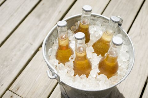a metal bucket full of ice with 5 bottles of beer on a table