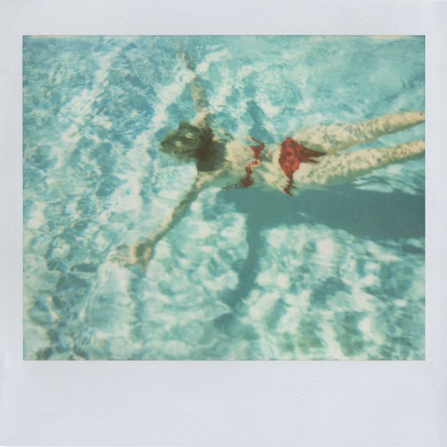 retro woman swimming pool, vintage summer woman in pool, swimming woman underwater relaxation concept for relaxing staycation, nostalgic memories of summer fun vacation, or healthy active lifestyles unrecognizable woman wearing red bikini on sunny day outdoors in tranquil turquoise water artistic full length portrait of confident woman, candid portrait with original polaroid edges on vintage photograph body distortion occurring from water ripples part of a series
