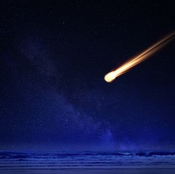 meteor in night sky falling over ocean