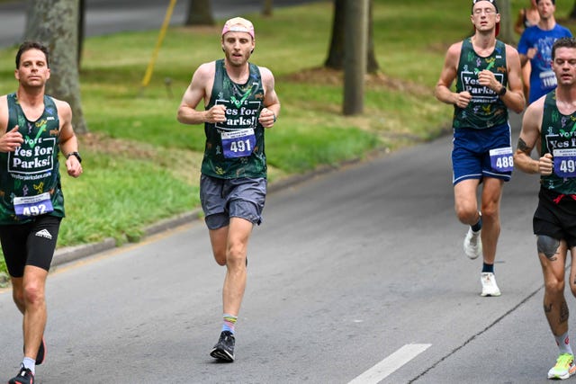 runners participating in a race wearing matching tank tops and numbered bibs