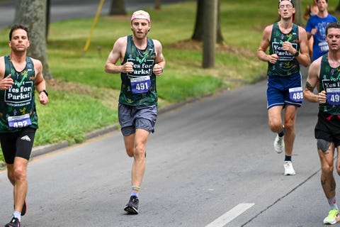 runners participating in a race wearing matching tank tops and numbered bibs
