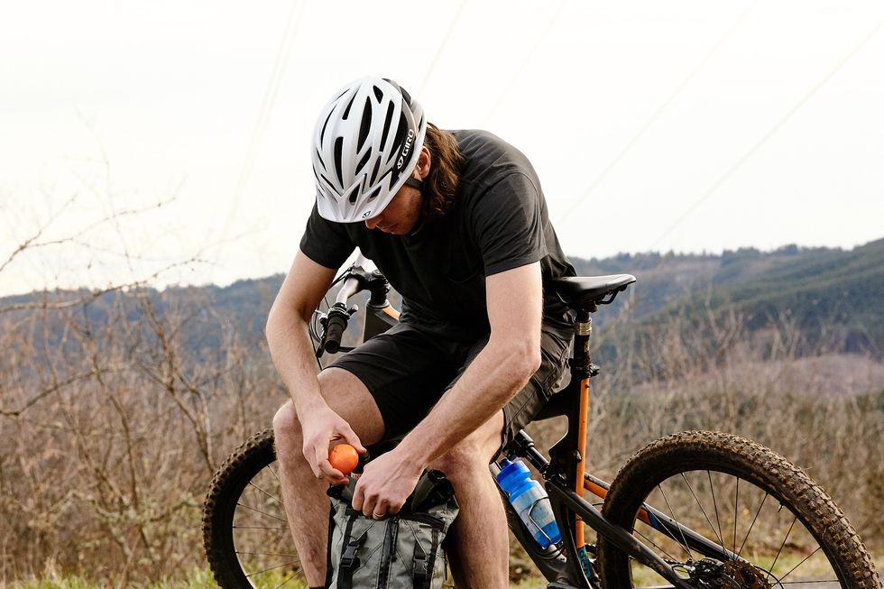 a mountain biker eating a tangerine during a ride