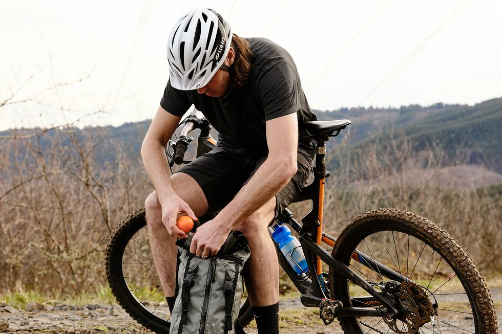 a mountain biker eating a tangerine during a ride