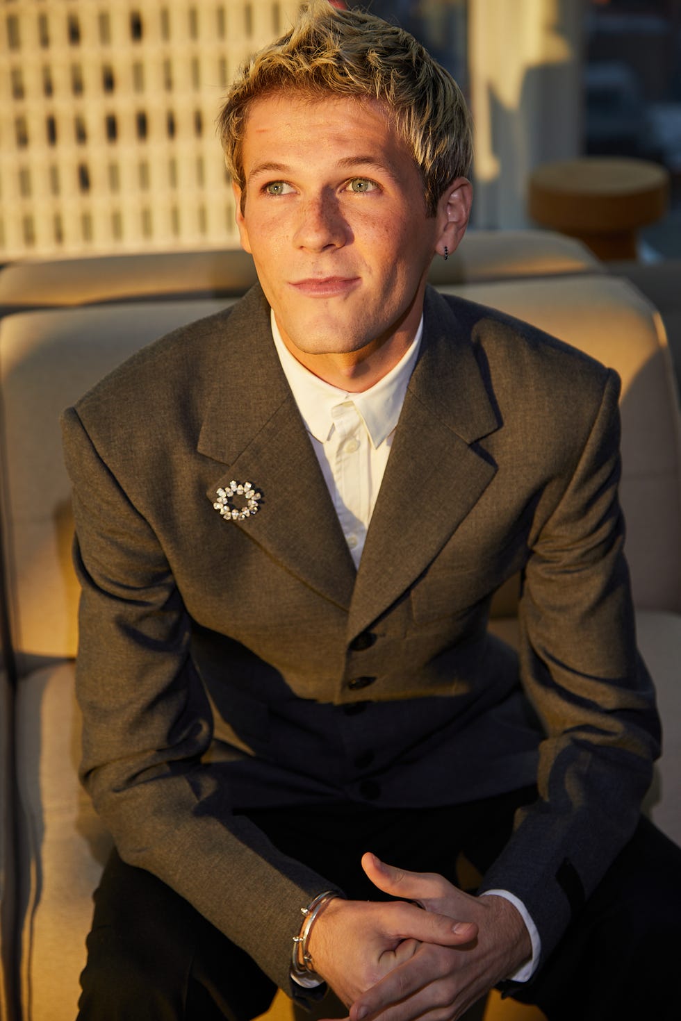 man sitting on a sofa in a formal suit with his arms crossed