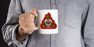 man holding a mug with poop emoji on the front