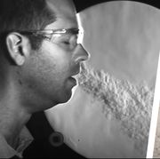 man exhaling vapor next to petri dish of coronavirus