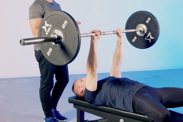 Man Doing Close Grip Bench Press with Trainer