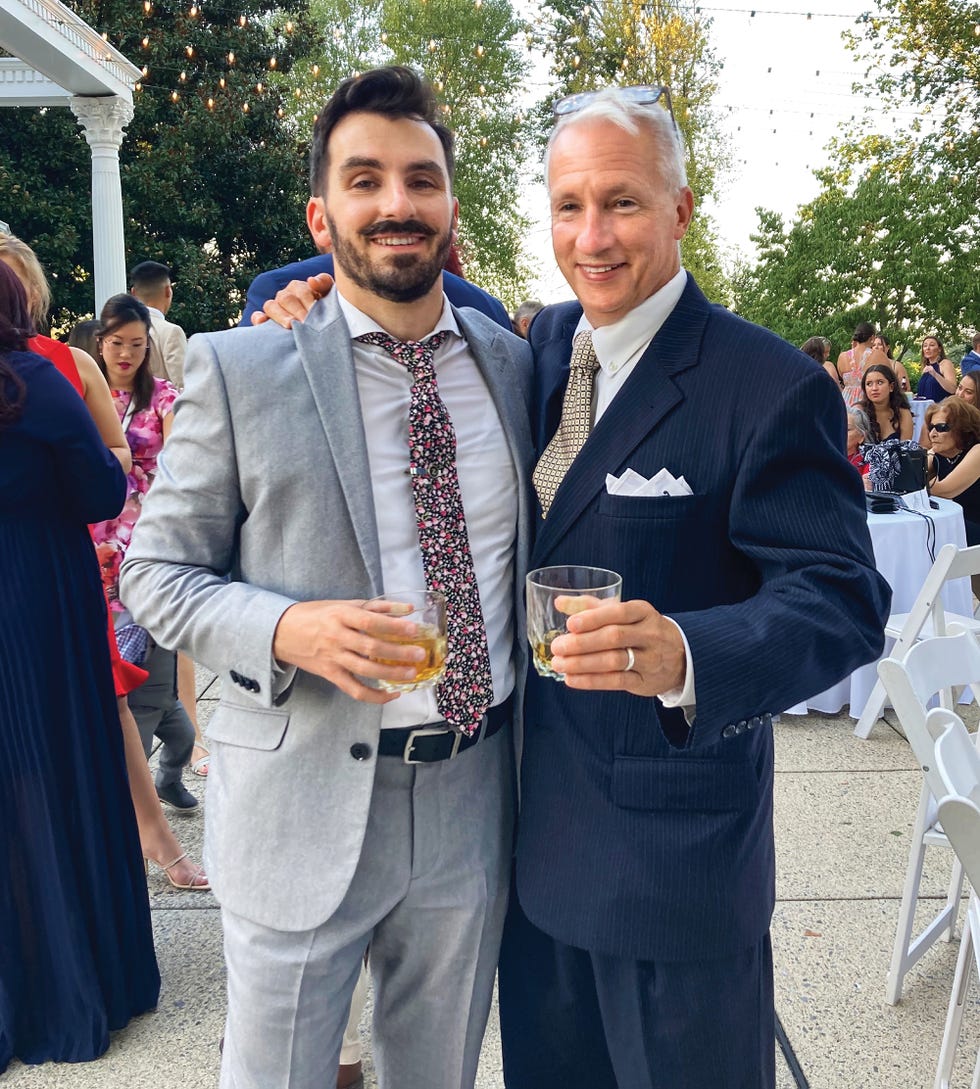 two men in formal attire holding drinks at a social event