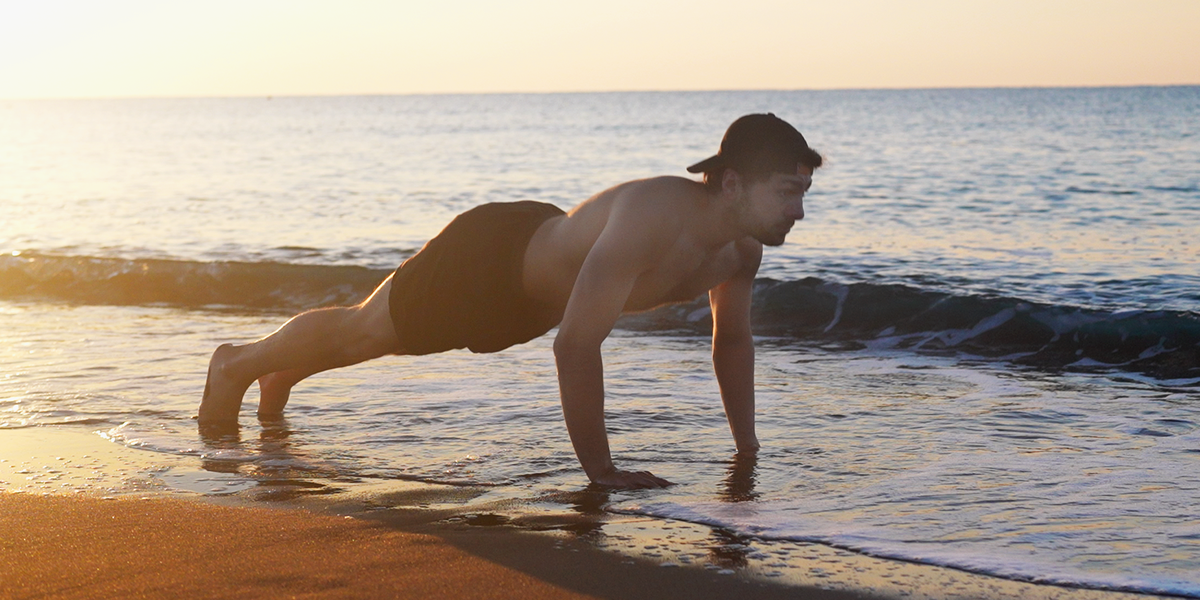 man doing pushup on the beach