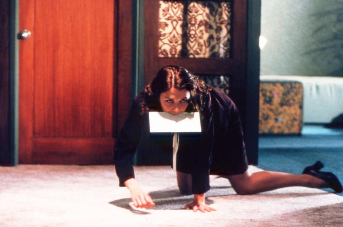 a still of a woman crawling on the floor with paper in mouth from the movie secretary