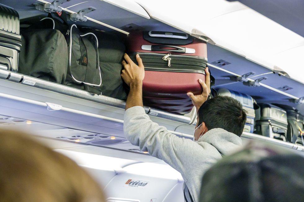 miami, florida, miami international airport mia terminal, flight departure passenger putting suitcase in overhead luggage bin