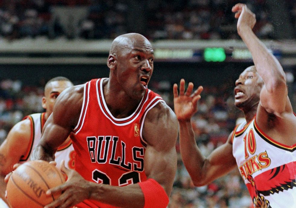 michael jordan holding the ball while driving past a defender