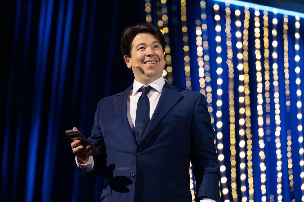 michael mcintyre on stage, dressed in a formal suit with a white shirt and a tie for michael mcintyre's big show season 7