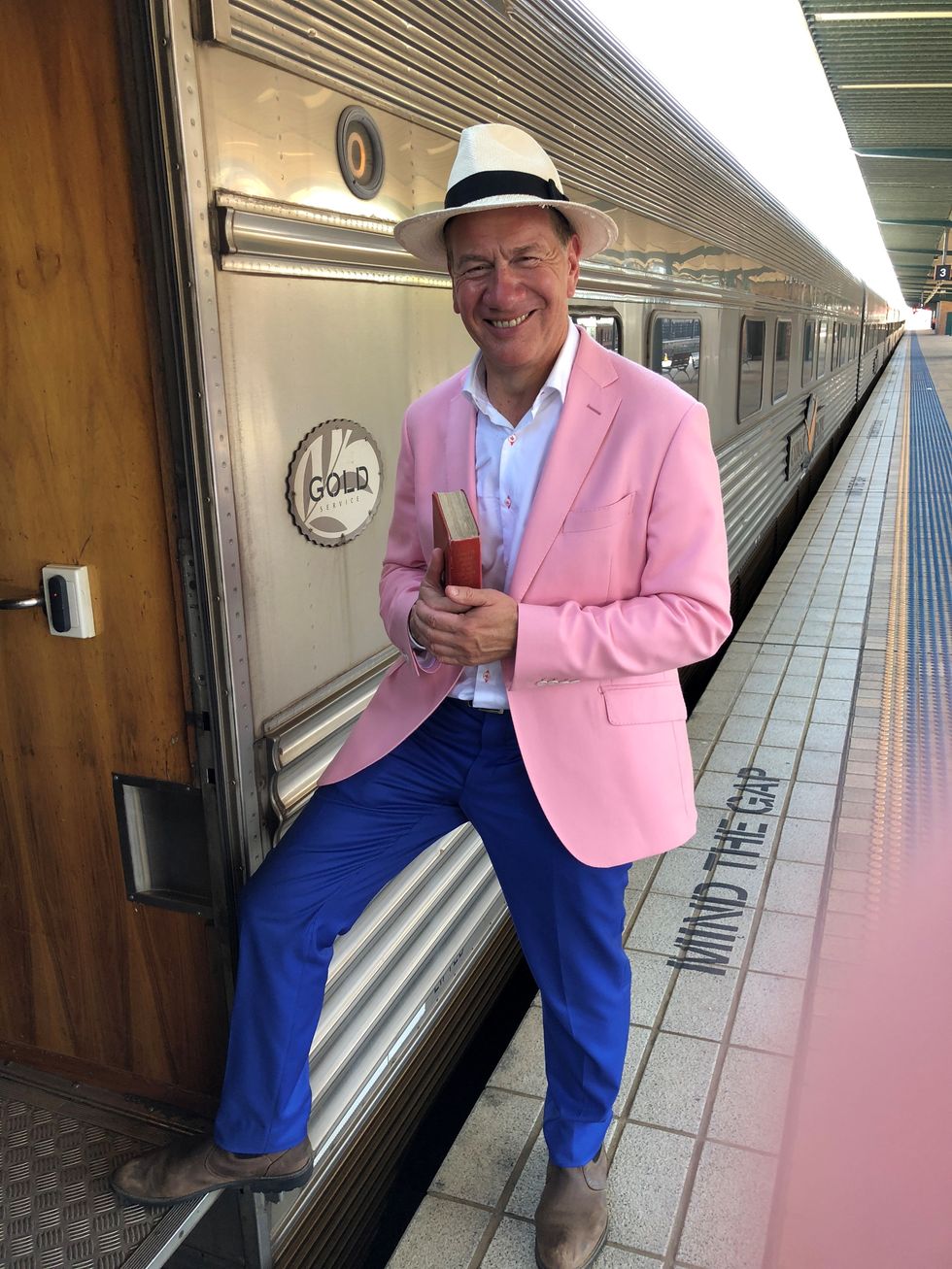 a man in a pink suit and white hat sitting on a train