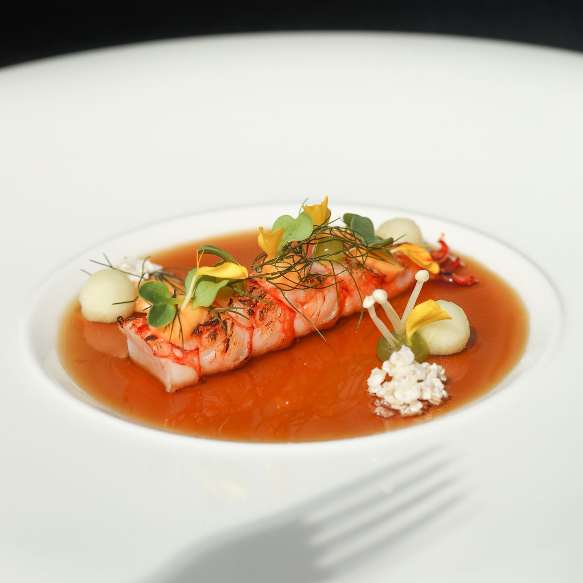 michelin star gourmet dish with prawn in seafood consomme with horseradish
