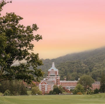 a building with a dome on top surrounded by trees and hills