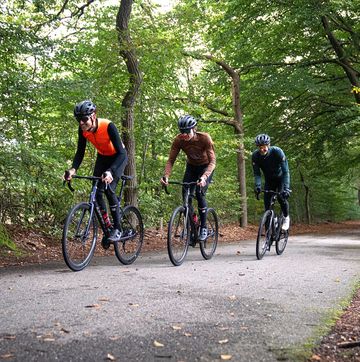 drie wielrenners rijden op een racefiets door het bos