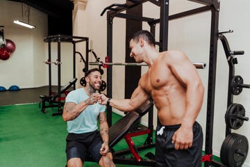 mid adult friends smiling while giving fist bump in health club