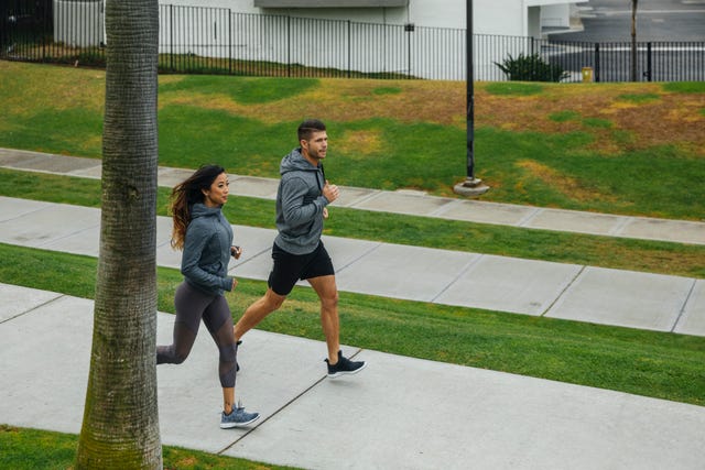 mid adult man and woman running on footpath at park