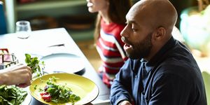 Mid adult man at dinner party holding plate and being served salad