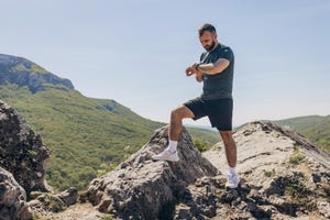 mid adult man checking his smart watch after reaching the top of the hill running